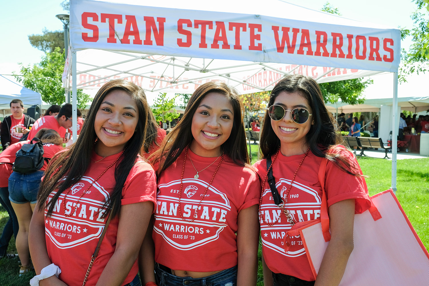 students in front of a stan state warriors sign