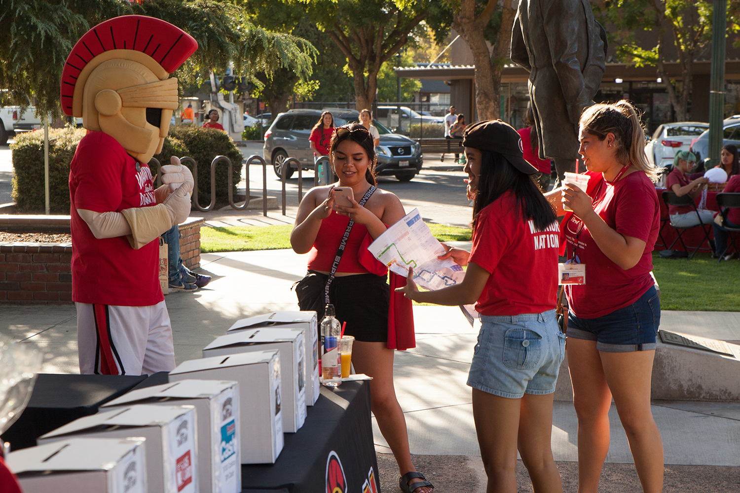 Three female students conversing with Titus mascot.