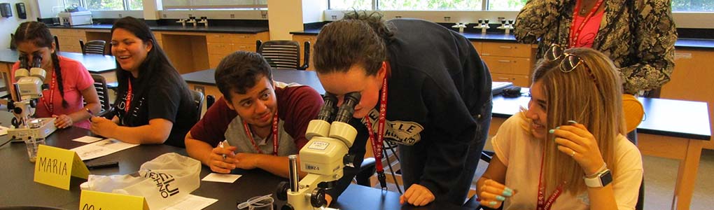 Students in a lab looking at a microscope.