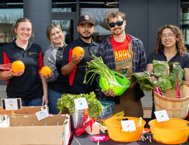 Four students at the StanFresh Market event hold their fresh produce in a group photo.