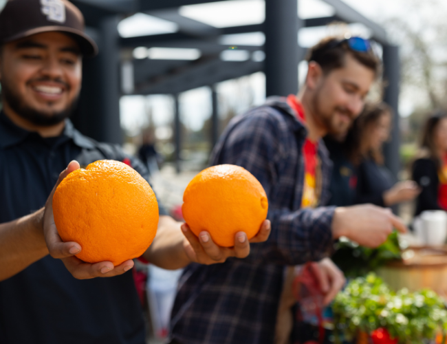 A student holds up two fresh picked oranges.