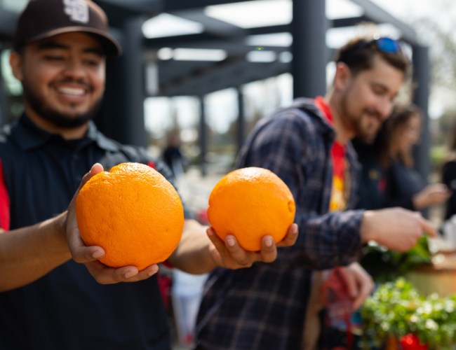 Student holding two oranges at the StanFresh Market event 2024.