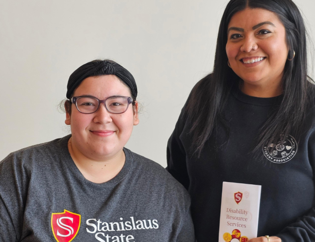 Two MSW students pose in a photo holding two brochures.