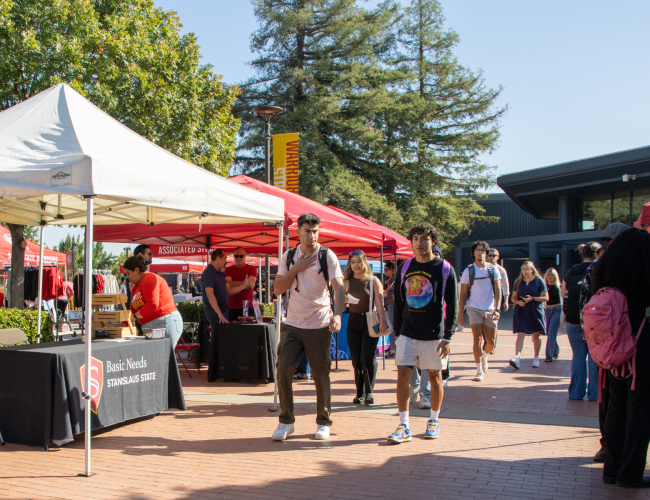 The quad is filled with students visiting various booths at Stan State.