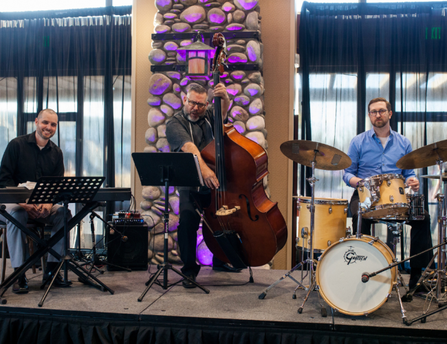 A band poses for a photo, playing music in a room filled with purple lighting.