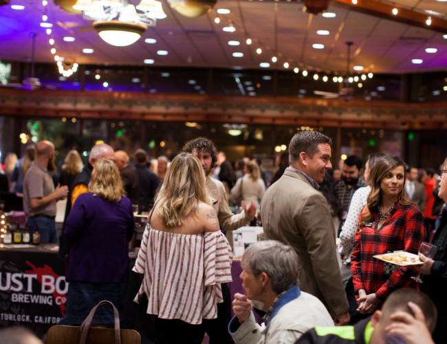 Guests socialize and celebrate at a party, gathered around tables adorned with decorations and refreshments.