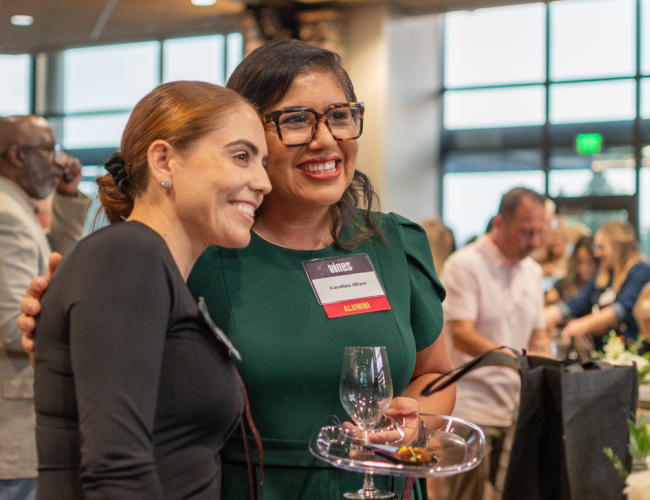 Two women are seen smiling during a lively event.