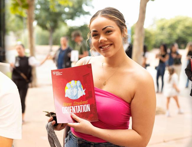 A newly admitted student poses with a copy of the NSO program booklet