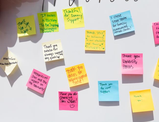 A whiteboard is adorned with sticky notes where community members expressed their thanks to Stan State