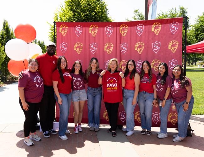 President Britt Rios-Ellis poses with 8 campus community members and donors at the 1960 campaign event