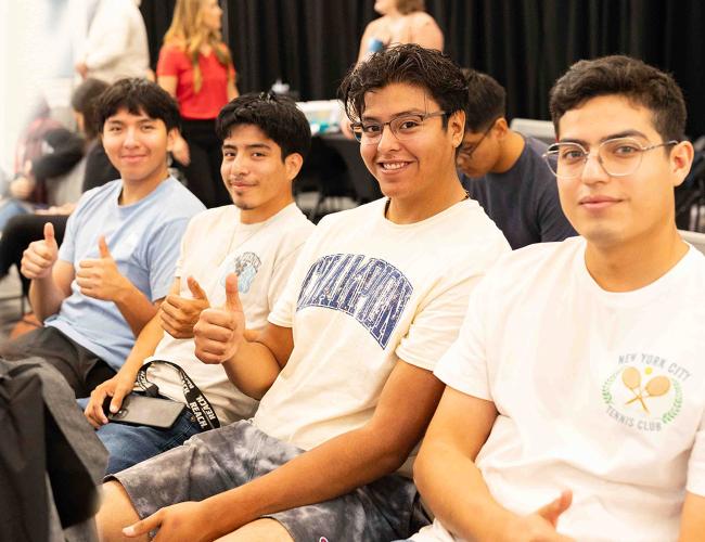 Group of four students sitting and smiling to the camera