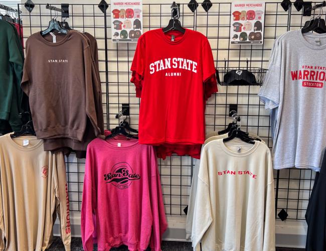 A wall displays various Stan State branded garments available for sale at the Stockton Campus