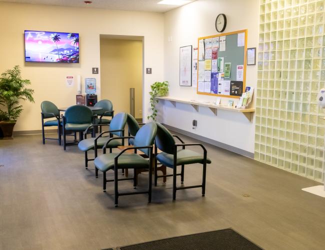 Health center waiting room with green chairs and bulletin board