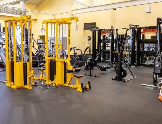 Fitness center with yellow cable machines and cardio equipment