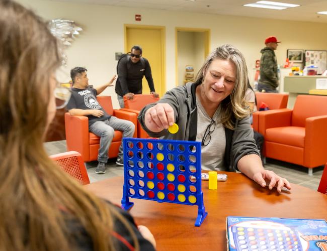 Woman playing connect four in student lounge