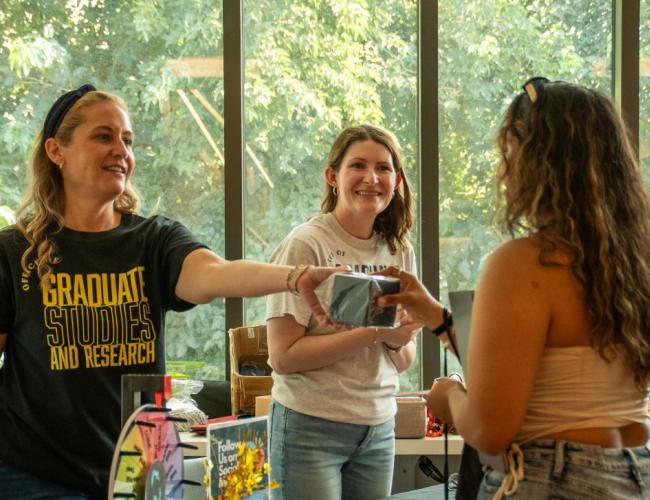 Staff from Grad Studies can be seen checking a student in for an event