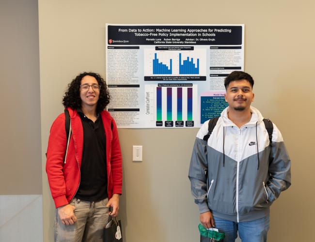 Two students pose near a research poster