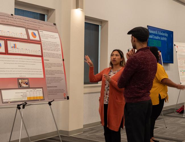 A student presents their research poster to a passerby