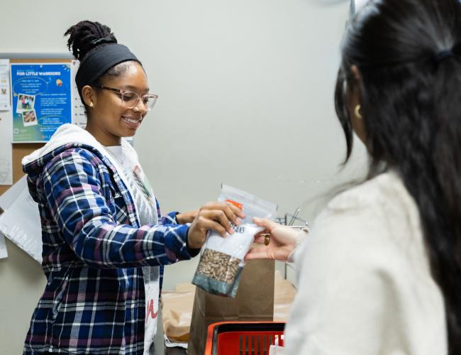 Staff member handing food items to student at pantry