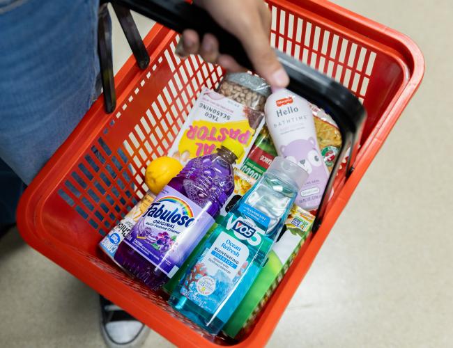 Student holding red basket with food and hygiene products