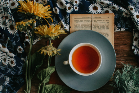 A cup of tea next to sunflowers. 