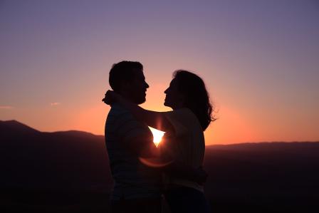 Silhouette of two individuals hugging.