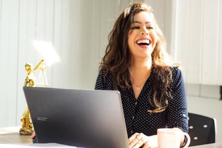 Student laughing while working on laptop.