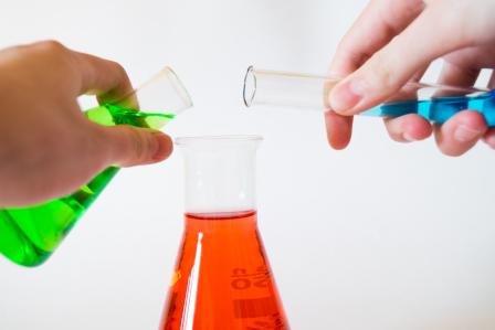 Three science test tubes, green, blue, and red