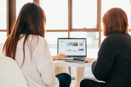 Two people at a table with laptop in front of them