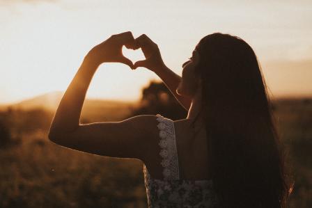 Person holding up a heart to the sunset
