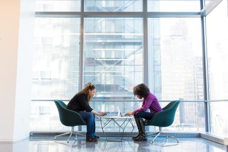 2 people sitting at a table communicating over work.