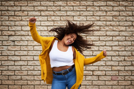 a woman dancing in front of a brick wall.