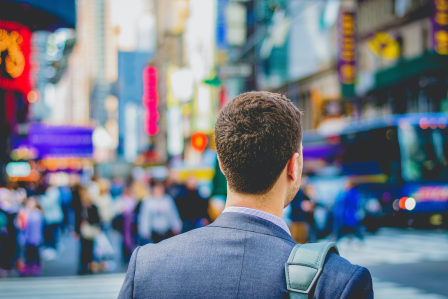 a man in a suit with a shoulder bag staring across the street