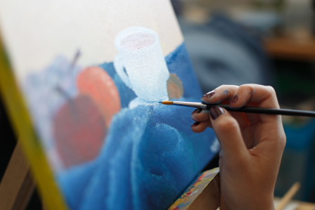 an artist painting an image of cups and fruit.