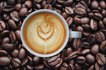 a cup of coffee sitting on coffee beans. 