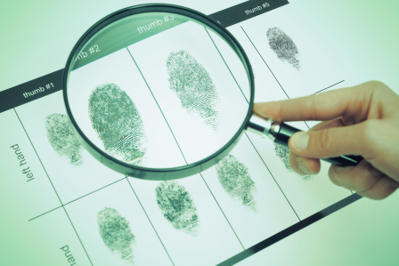 Magnifying glass moving over a line of finger prints.