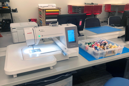 a CNC embroidery machine sitting on a table next to thread