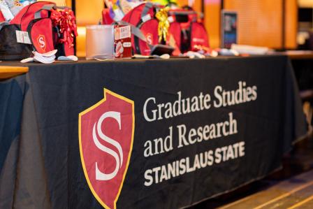 Tabling with giveaway items and logo for Graduate Studies and Research at Stanislaus State