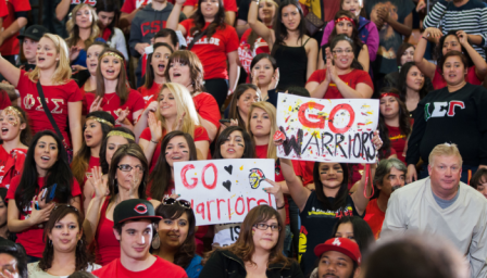 A crowd of students cheers from the bleachers at Stan State homecoming basketball game.