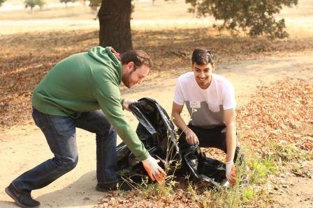 Students outdoors with a trash bag picking up litter