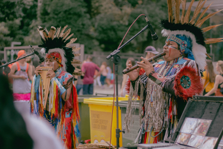 Two men wearing traditional headdresses play musical instruments, showcasing cultural heritage and artistry.