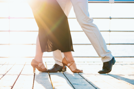 A couple engaged in a dance on a wooden deck.