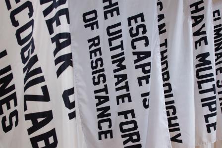 White flags with messages of resistance, adorned in black bold text.