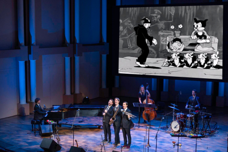 The Queen's Cartoonist performing on stage.