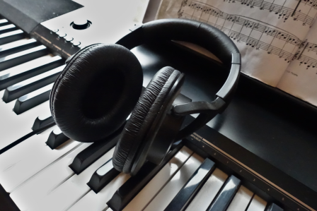 Headphones and music sheets on top of a piano