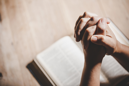 Hands praying over a Bible