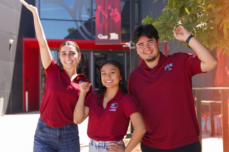 Three students in a group picture by the Student Center's main entrance