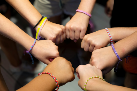 People, with bracelets on, putting their hands together
