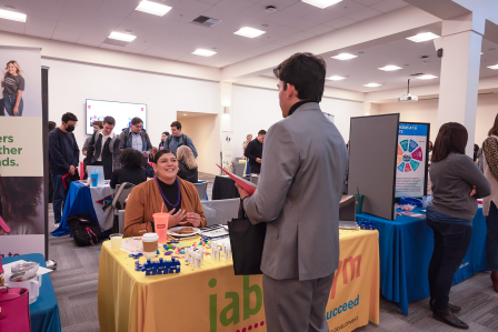Employers at tables talking with students in professional attire
