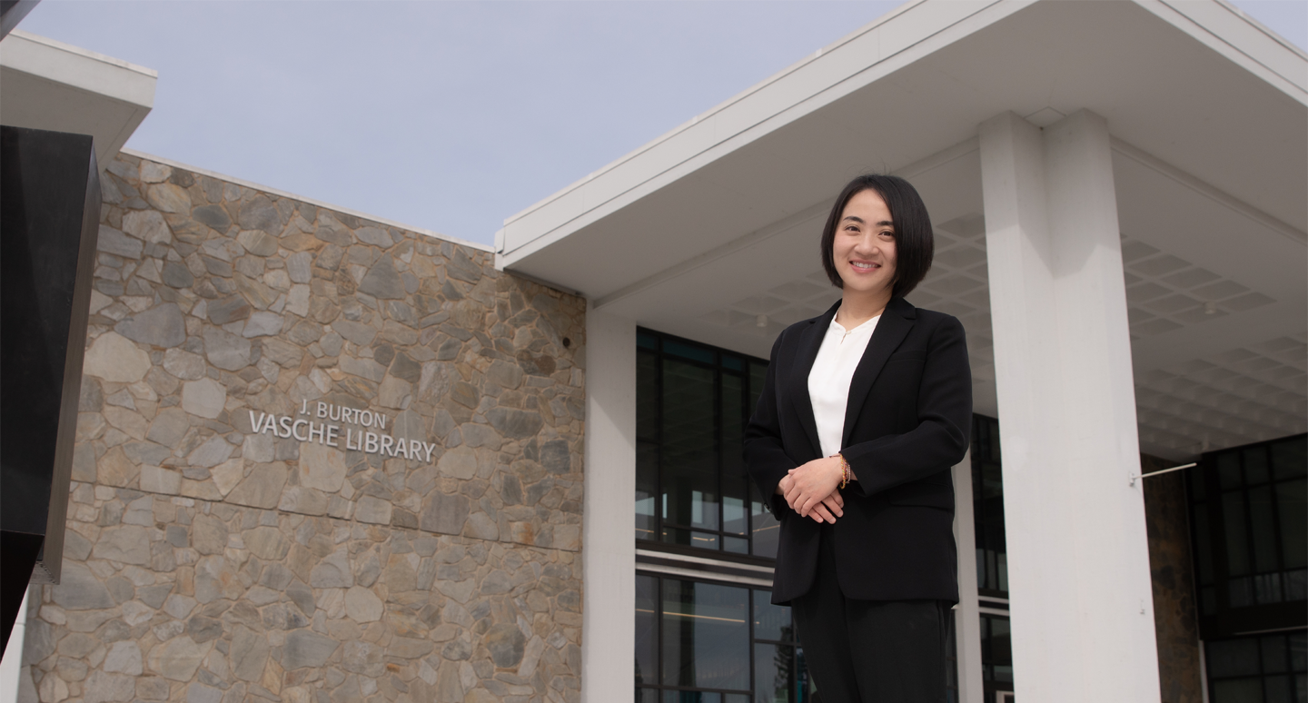 Doctor Xiao Xiao poses in front of the John Vasche Library at Stan State.